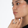 Close-up of a woman wearing a diamond  and sterling silver love knot ring on a plain background